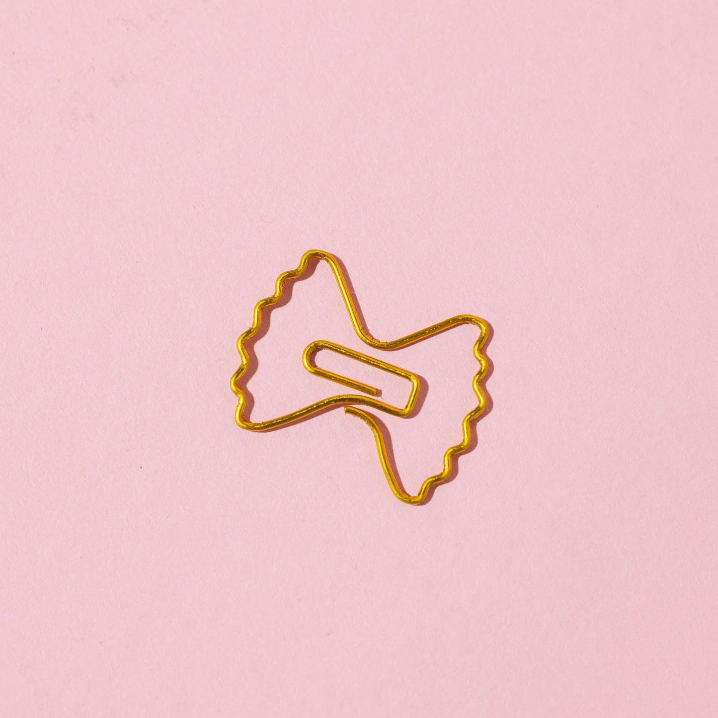 Gold paper clip on a pink background