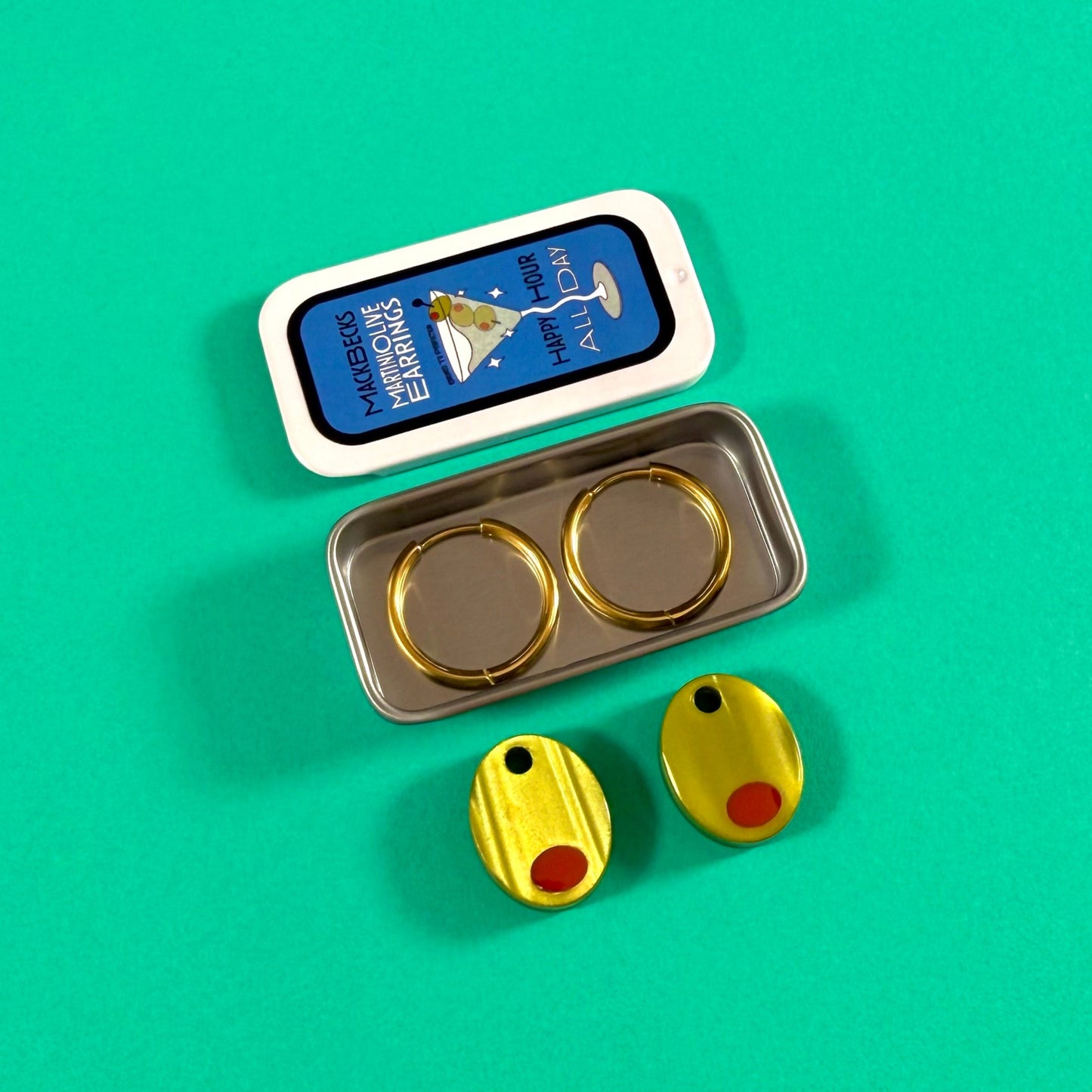 Olive earrings in a collectible martini themed MackBecks tin on a green background.
