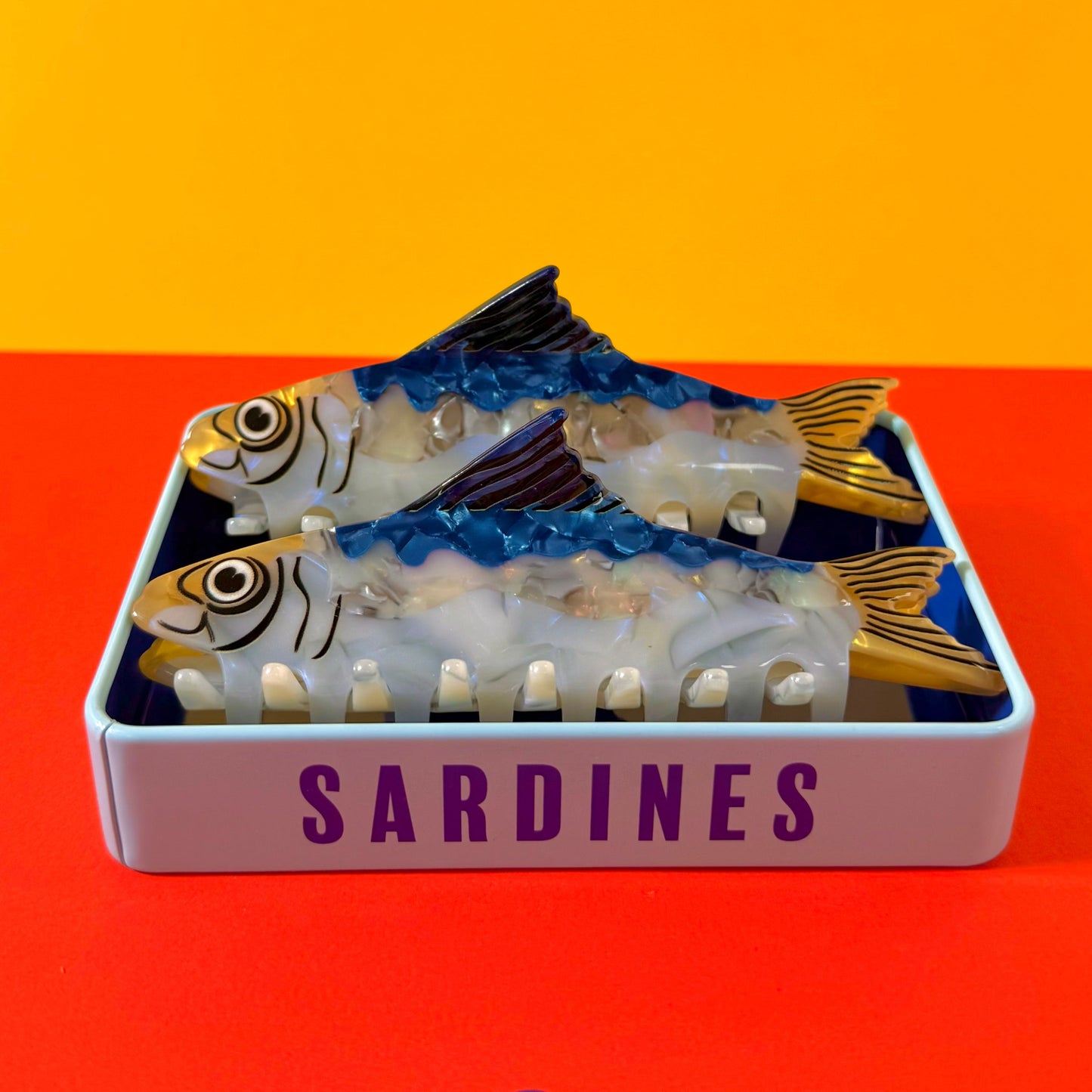 Can of sardine hair claws on red and yellow background.