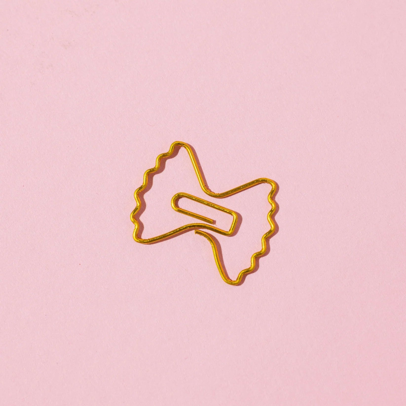 Gold paper clip on a pink background