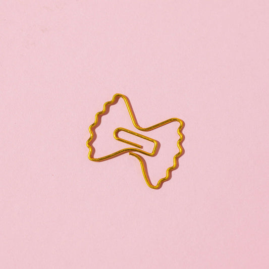 Gold paper clip on a pink background