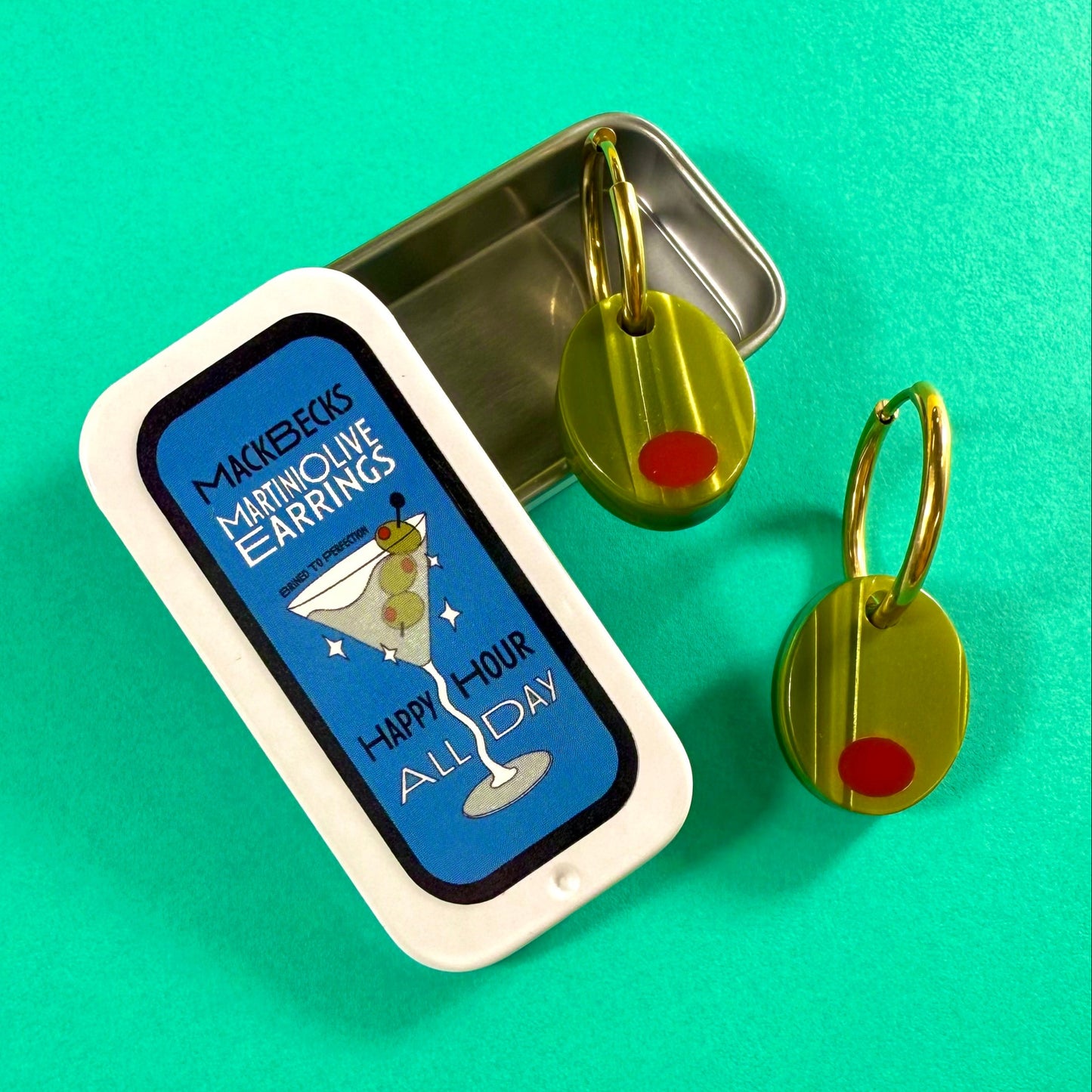 Olive earrings in a collectible martini themed MackBecks tin on a green background.