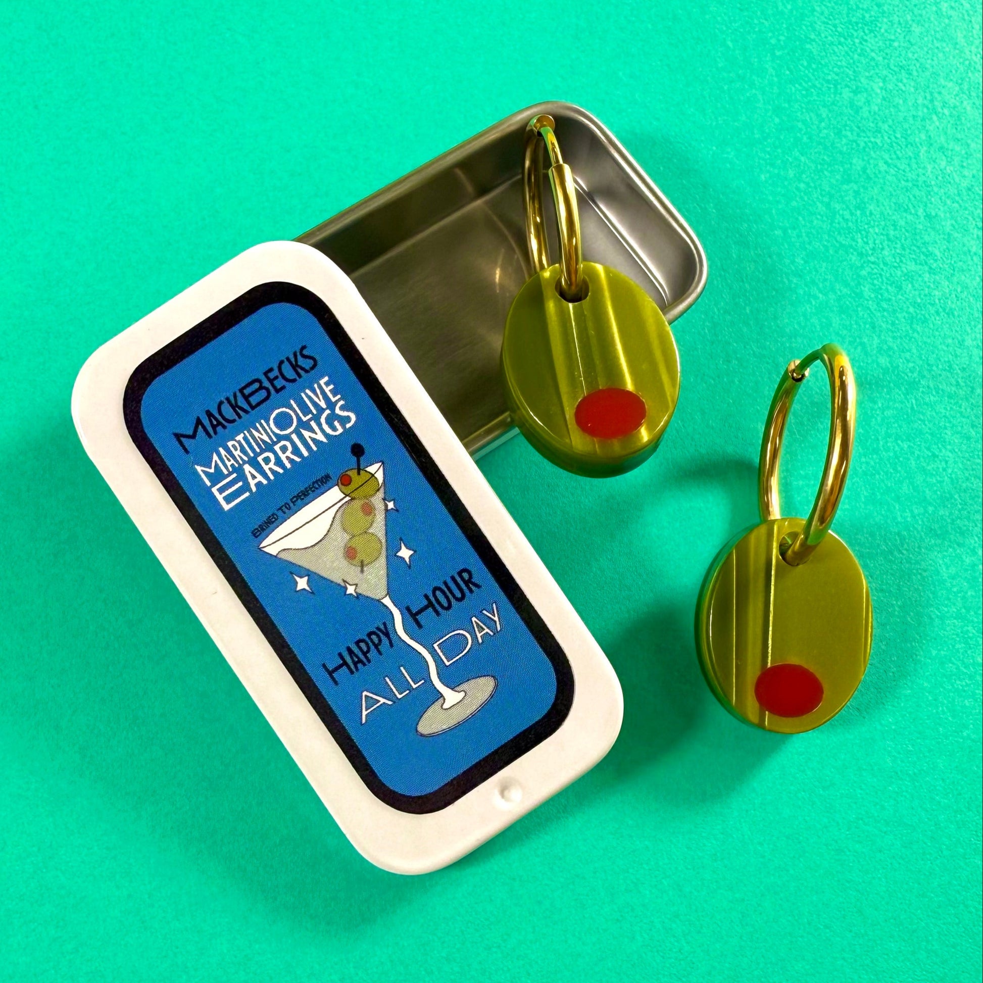 Olive earrings in a collectible martini themed MackBecks tin on a green background.