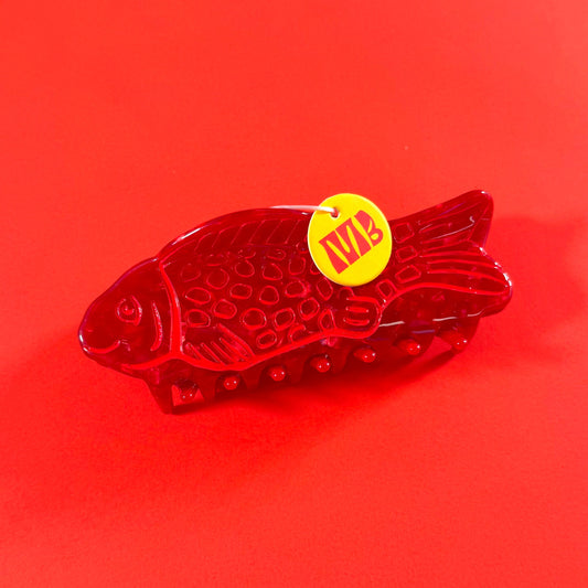 Red fish-shaped hairclaw with a yellow MackBecks label on an red background